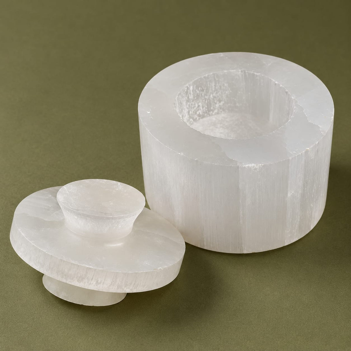 Boîte cylindrique en sélénite fermée sur fond bordeaux — écrin spirituel artisanal fait main au Maroc, cadeau bien-être unique | Pure Selenite
